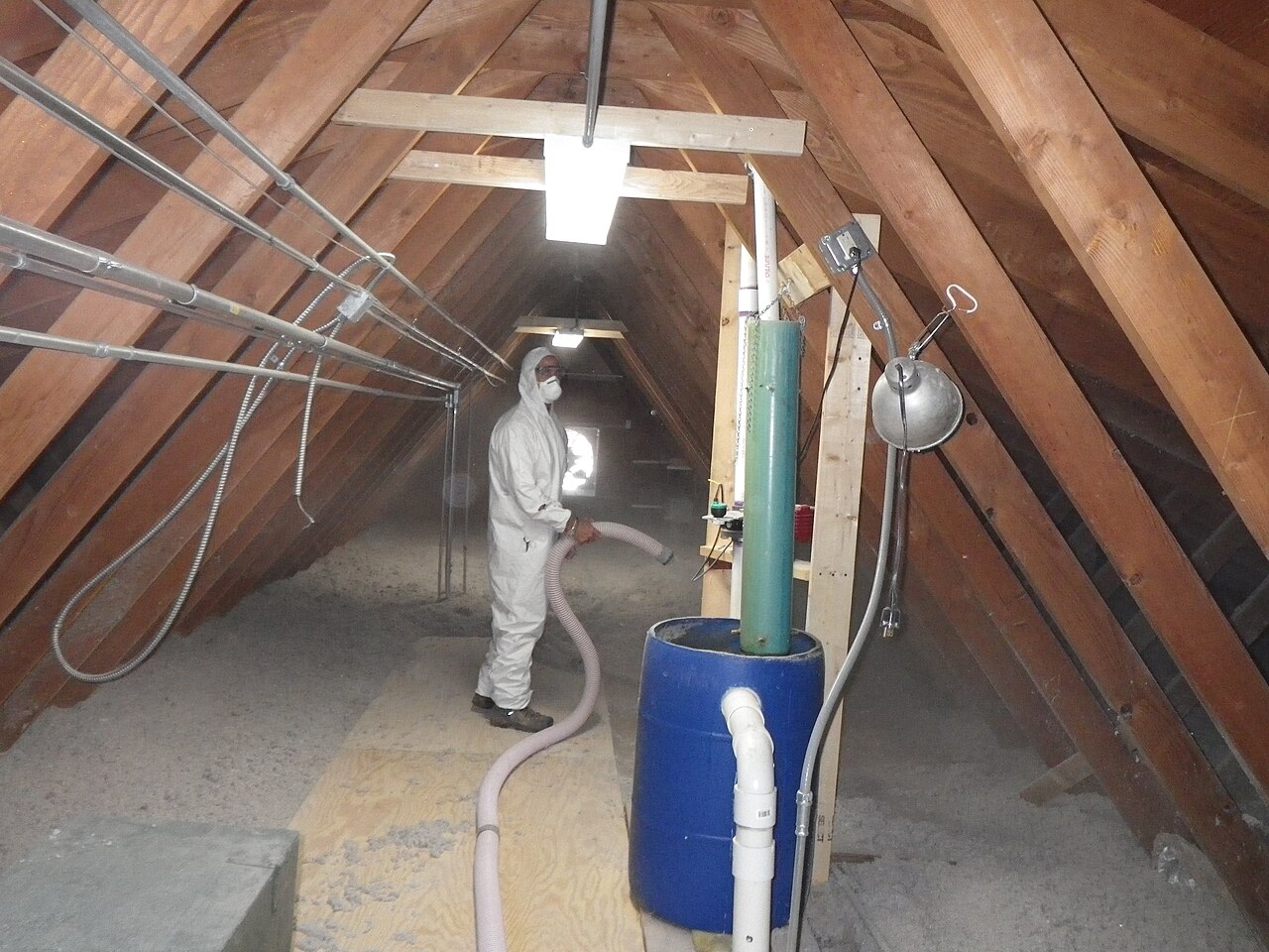 Technicien soufflant de l'isolant en vrac dans un entretoit